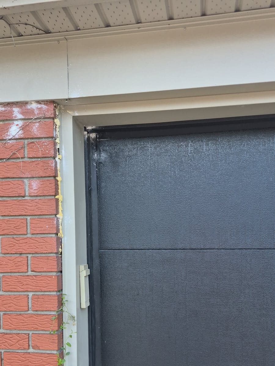 The same garage doorway at the follow-up visit, with the glue board removed and the foam still in place along the brickwork.